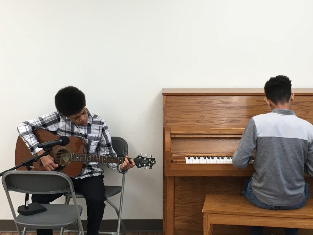 One man playing the guitar and another man playing the piano