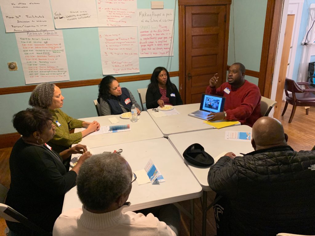 7 members sitting at a large table discussing